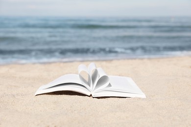 Photo of Open book on sandy beach near sea
