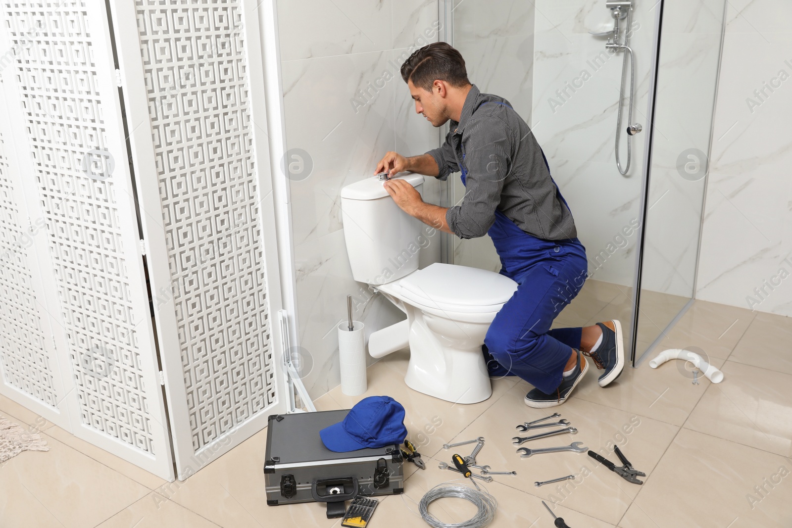 Photo of Professional plumber working with toilet bowl in bathroom