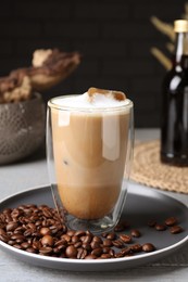 Photo of Glass of aromatic coffee with syrup and beans on light grey table