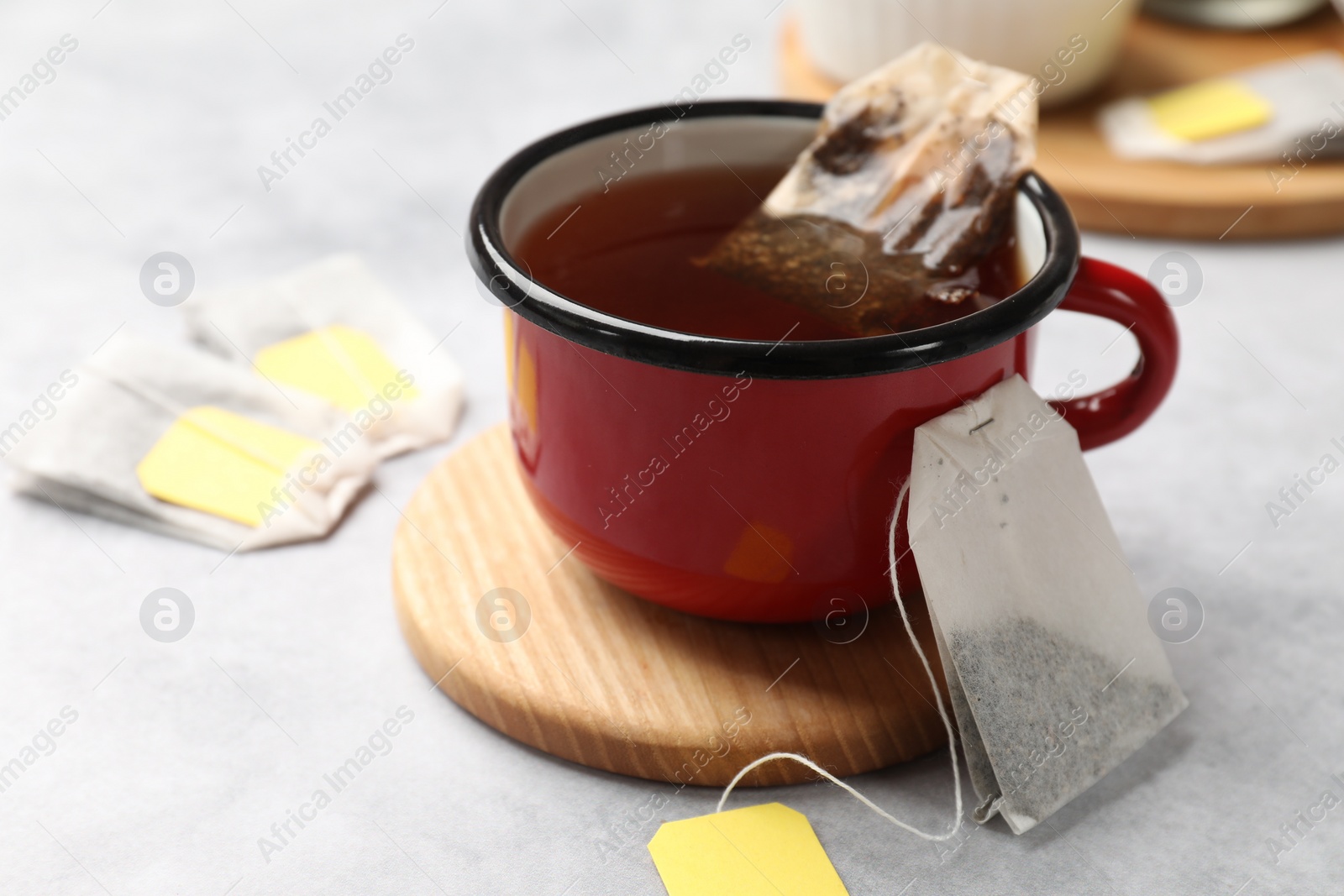 Photo of Tea bags and cup of hot beverage on light table, closeup