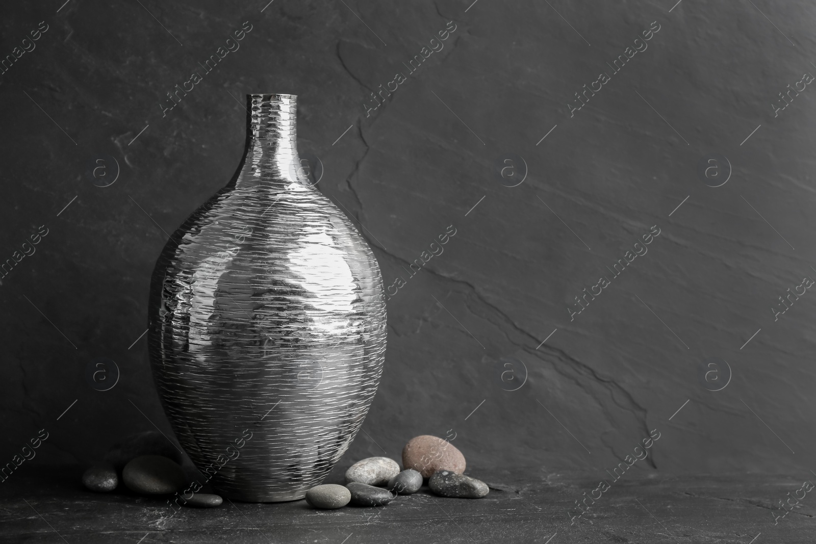 Photo of Stylish silver ceramic vase and rocks on black table, space for text