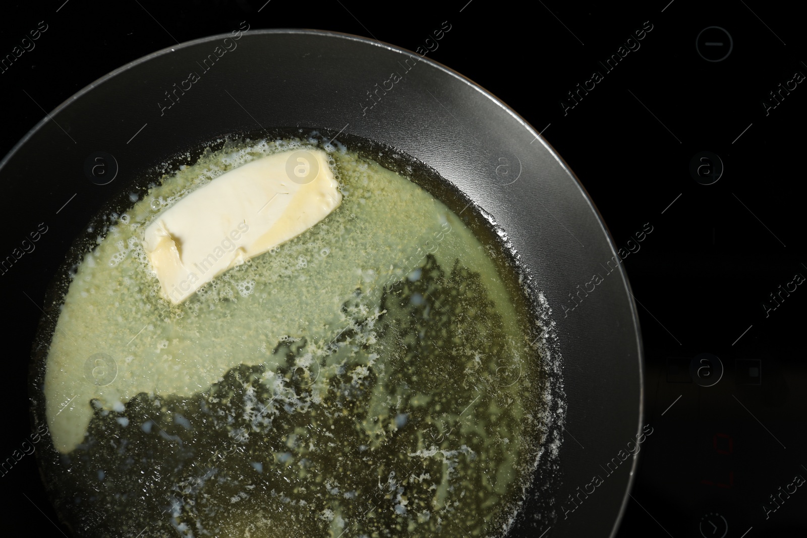 Photo of Melting butter in frying pan on cooktop, top view