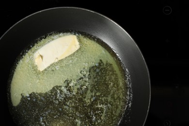 Photo of Melting butter in frying pan on cooktop, top view