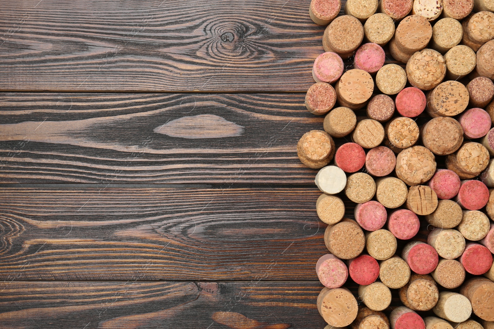 Photo of Many corks of wine bottles on wooden table, top view. Space for text