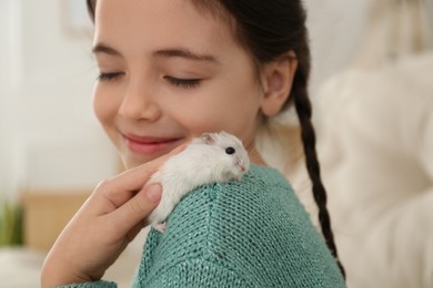 Photo of Little girl with cute hamster at home, closeup