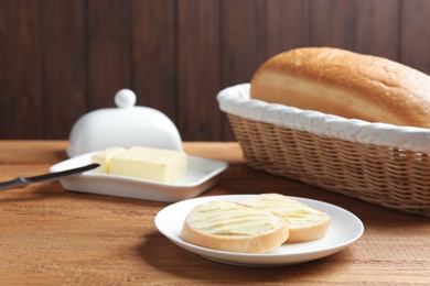 Photo of Slices of tasty fresh bread with butter on wooden table