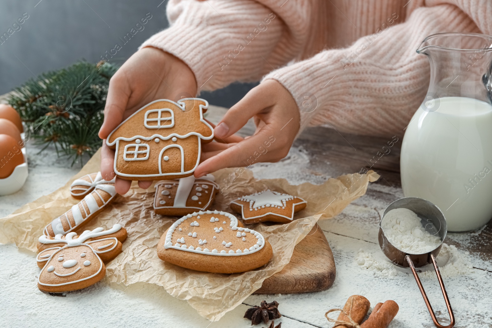 Photo of Woman holding delicious homemade Christmas cookie at wooden table, closeup