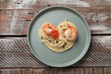 Photo of Heart made of tasty spaghetti, tomato, shrimps and cheese on wooden table, top view
