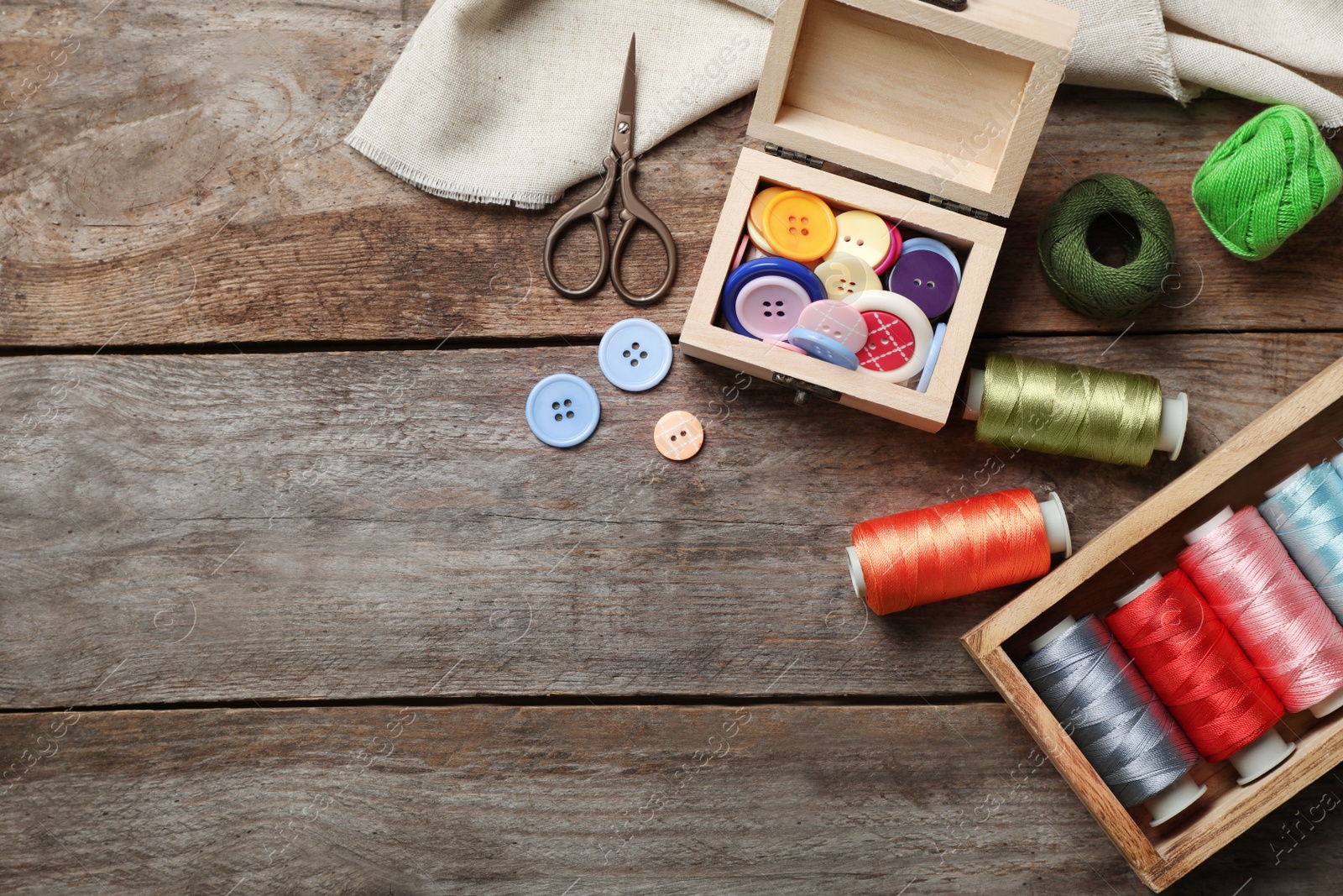 Photo of Composition with threads and sewing accessories on wooden background, top view