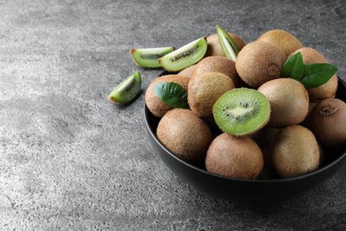 Photo of Fresh ripe kiwis in bowl on grey table, space for text