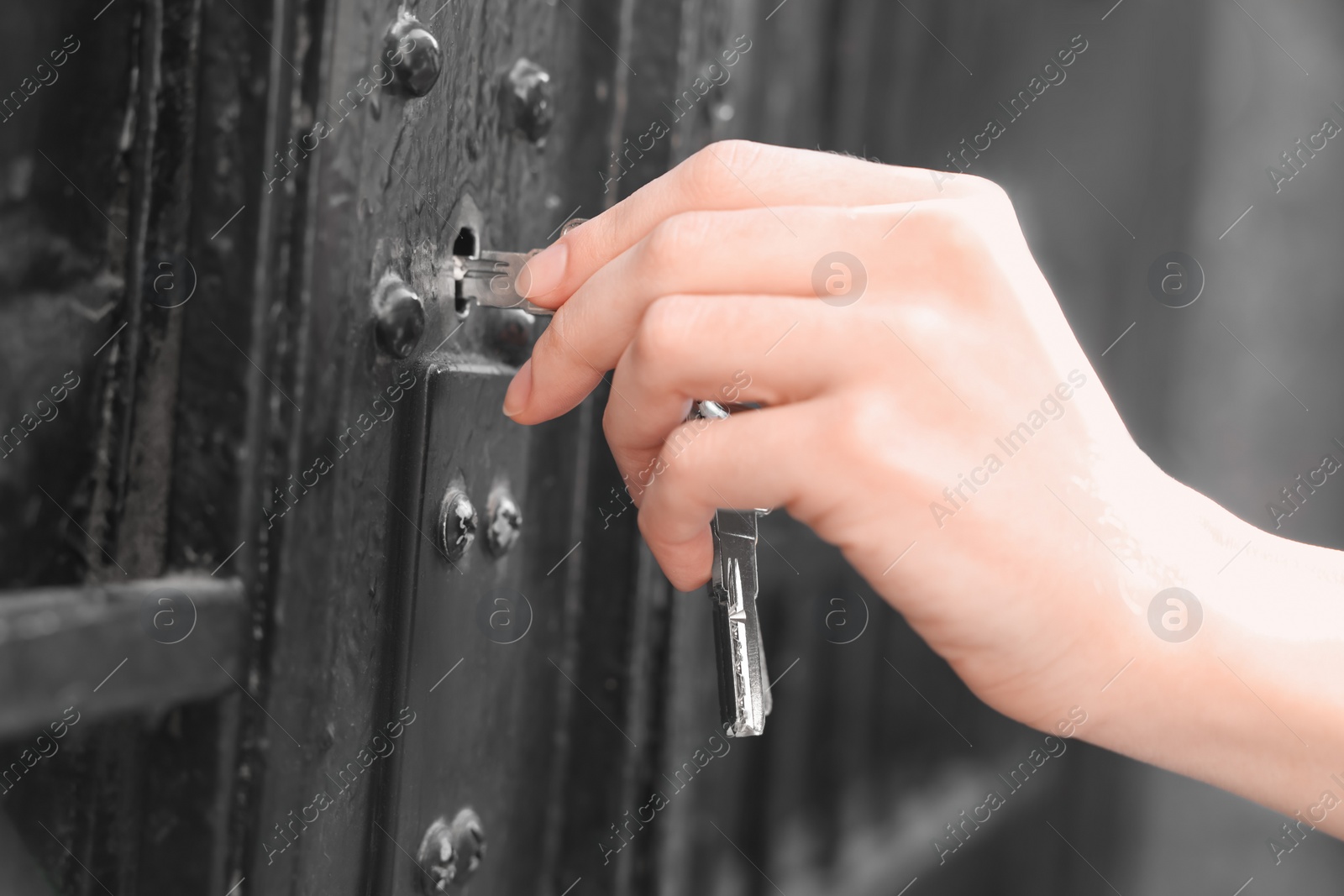 Photo of Woman opening door with key outdoors, closeup