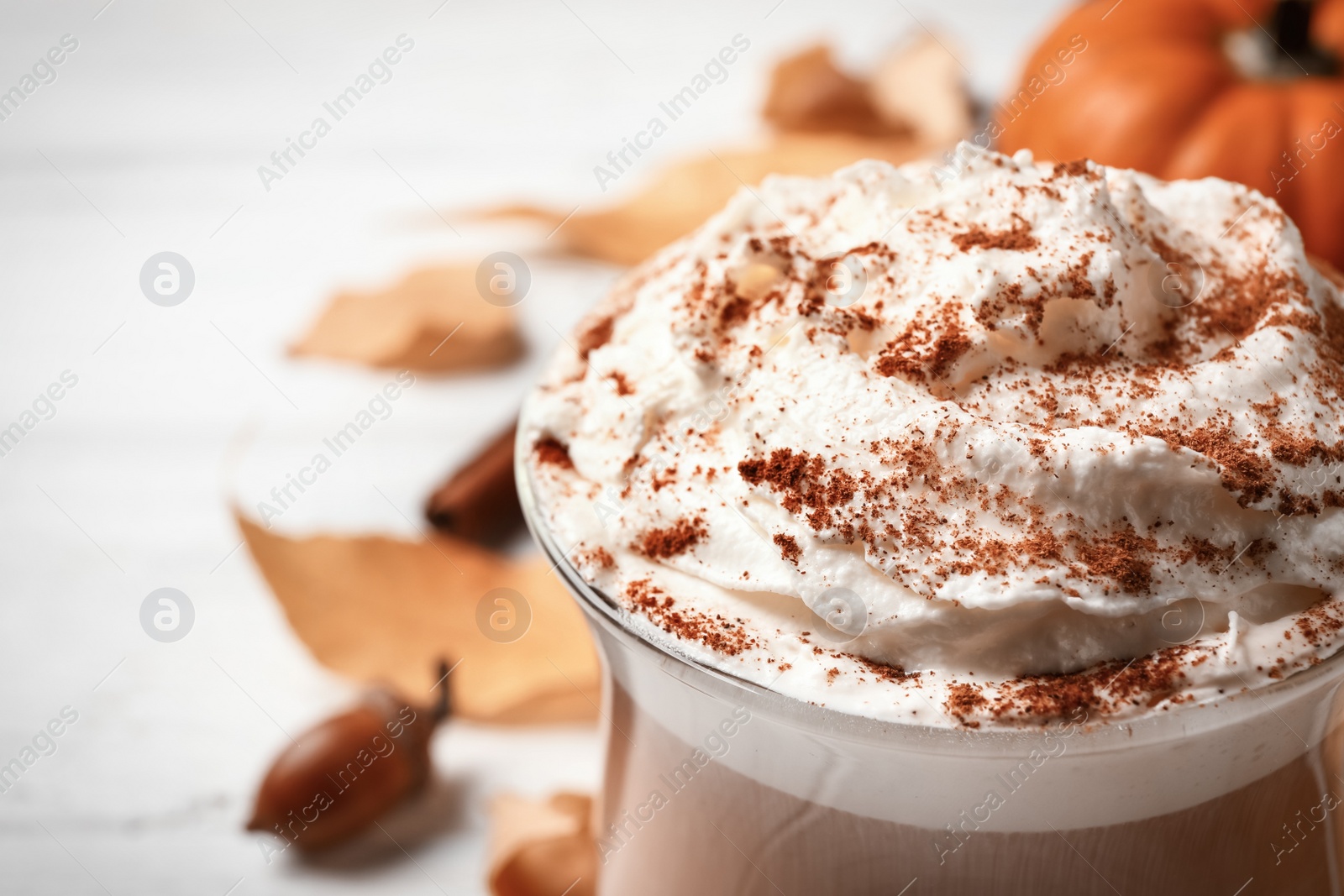 Photo of Delicious pumpkin latte on white table, closeup