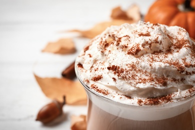 Delicious pumpkin latte on white table, closeup