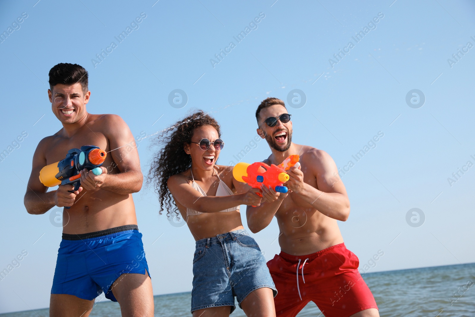 Photo of Friends with water guns having fun near sea