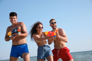 Friends with water guns having fun near sea