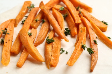 Photo of Tasty sweet potato fries on parchment, closeup