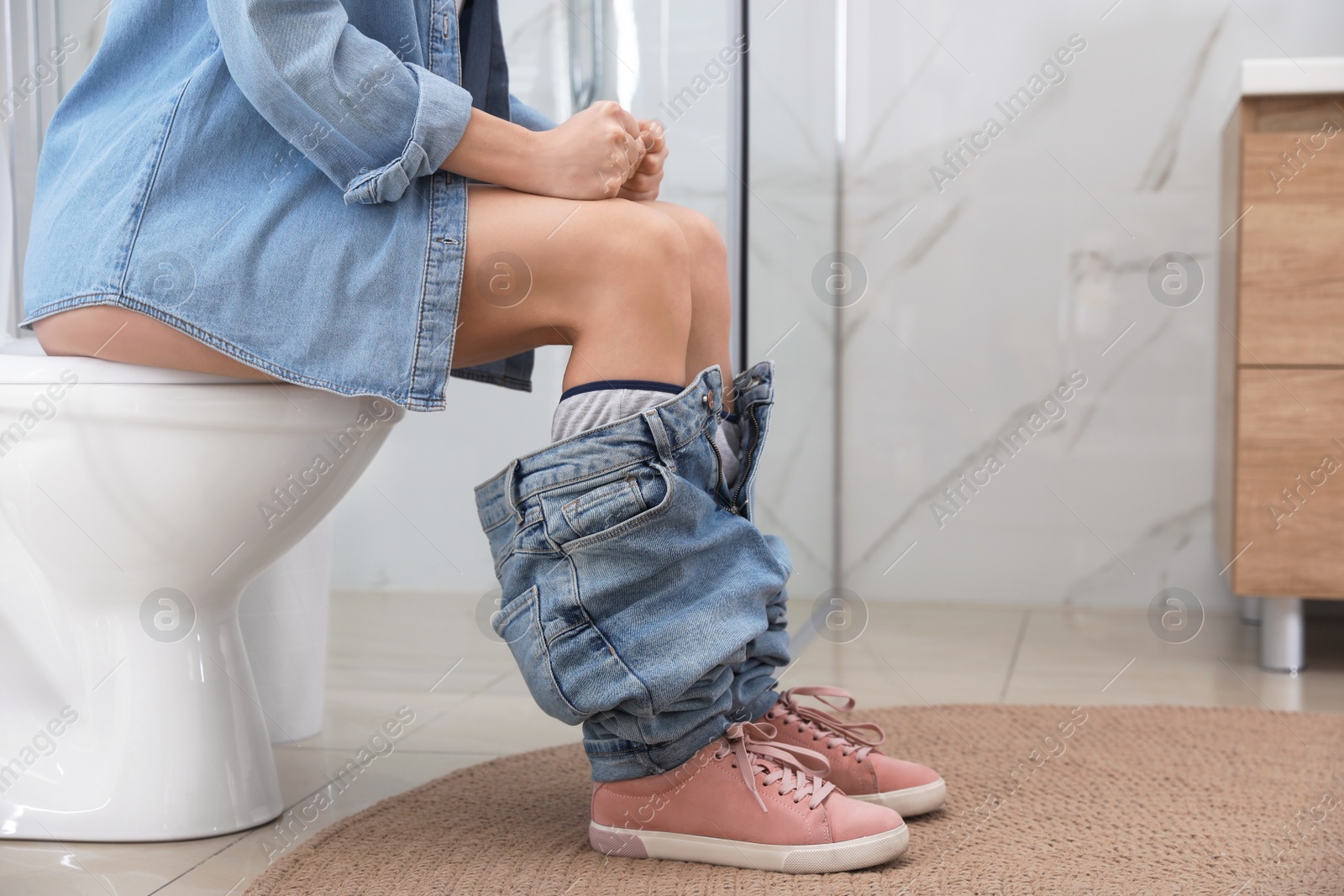 Photo of Woman suffering from hemorrhoid on toilet bowl in rest room, closeup