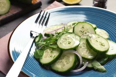 Photo of Plate with tasty cucumber salad and fork on the table, closeup