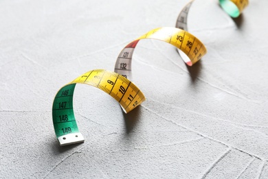 Photo of Measuring tape on grey background, closeup. Tailoring equipment