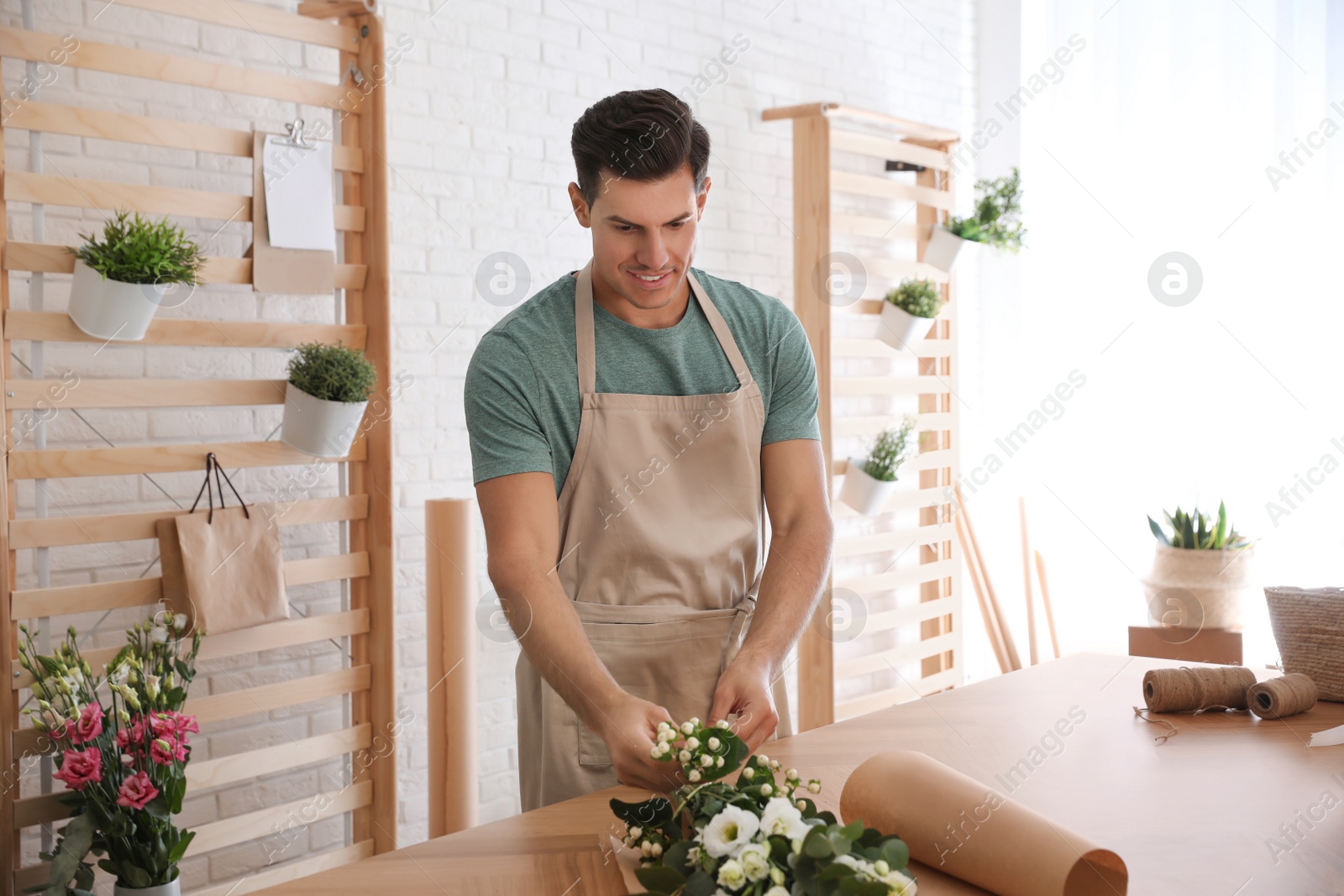 Photo of Florist making beautiful bouquet at table in workshop