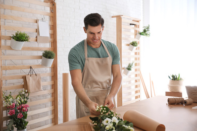 Photo of Florist making beautiful bouquet at table in workshop