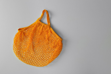 Photo of Empty orange net bag on white background, top view. Space for text