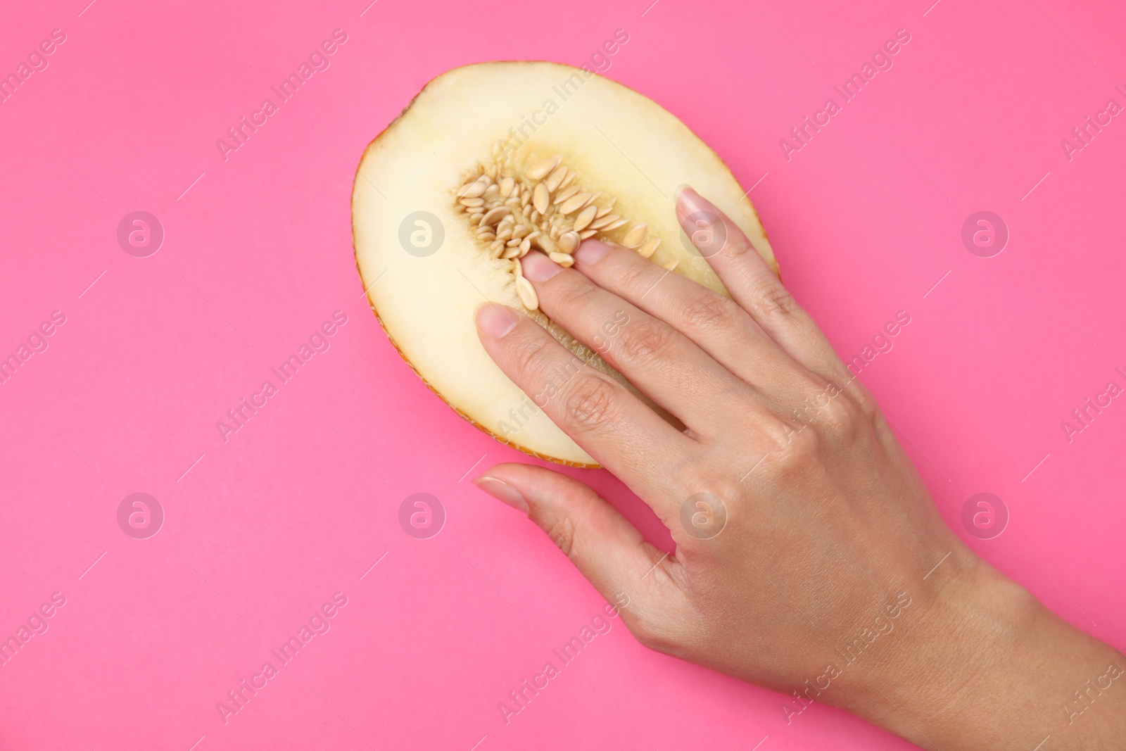 Photo of Young woman touching half of melon on pink background, top view. Sex concept