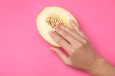 Photo of Young woman touching half of melon on pink background, top view. Sex concept