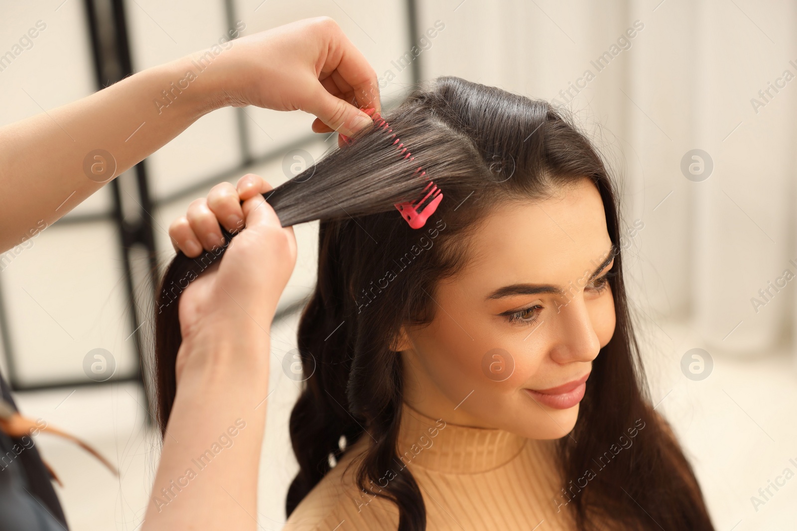 Photo of Hair styling. Professional hairdresser combing woman's hair indoors, closeup