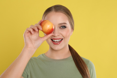 Photo of Young woman with apple on yellow background. Vitamin rich food