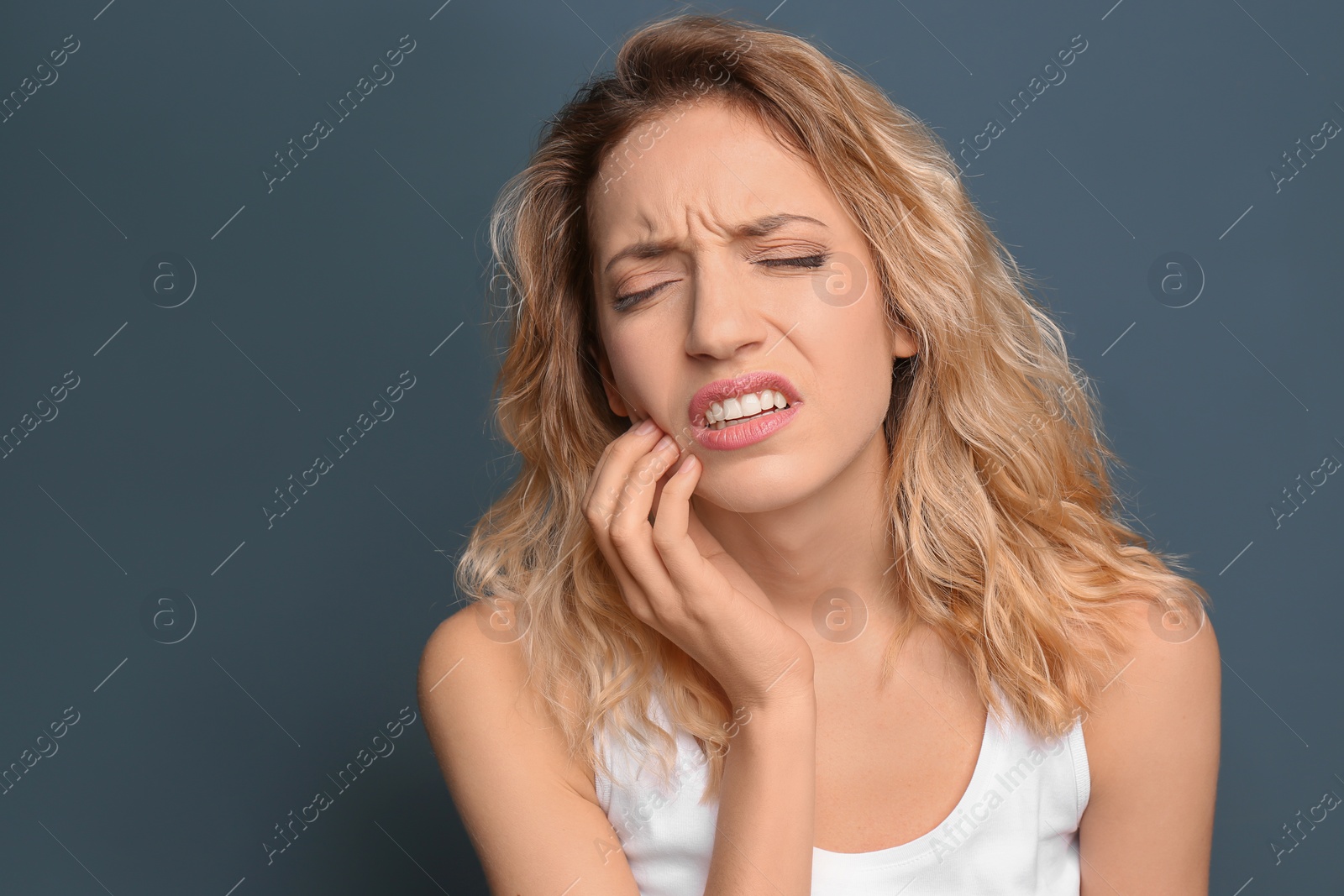 Photo of Young woman suffering from toothache on color background