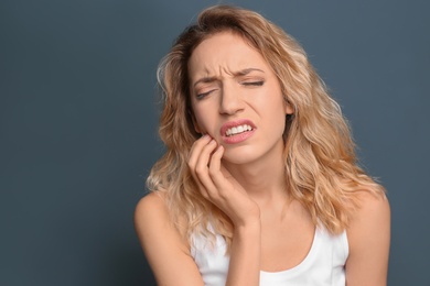 Photo of Young woman suffering from toothache on color background