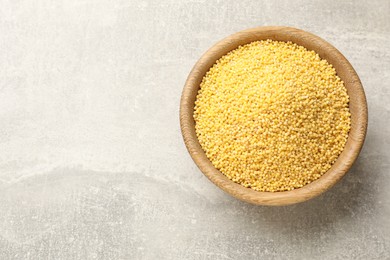 Photo of Millet groats in bowl on light grey table, top view. Space for text