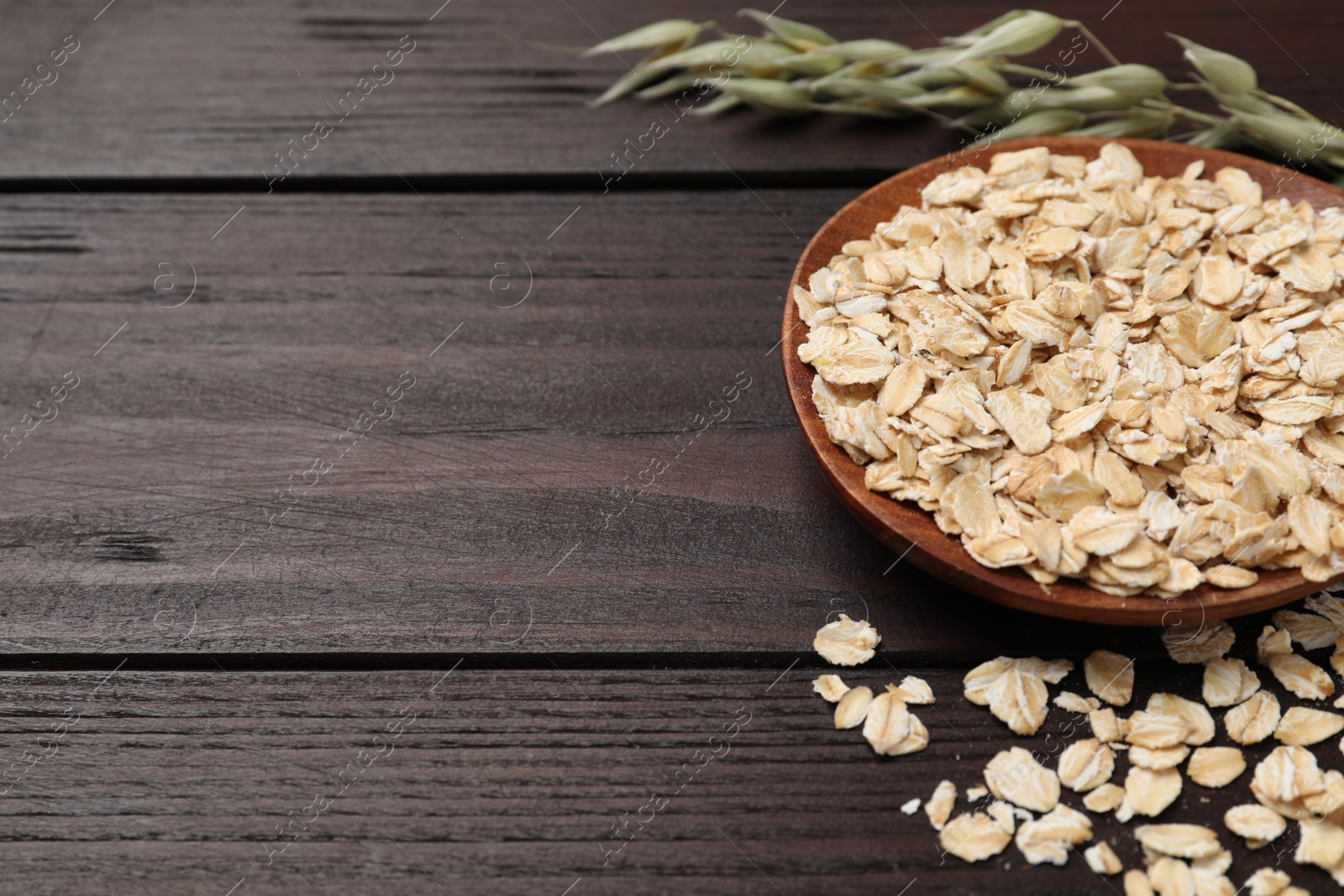 Photo of Oatmeal and florets on dark wooden table, closeup. Space for text