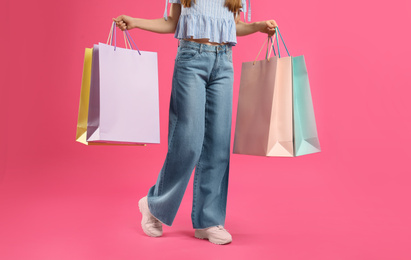 Photo of Young woman with paper shopping bags on pink background, closeup