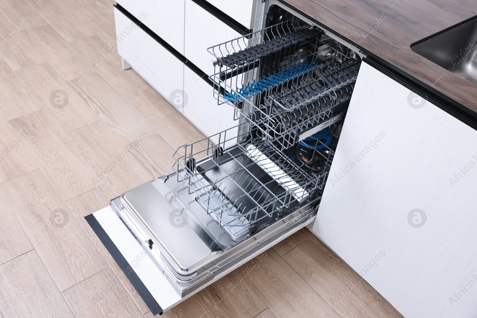 Photo of Open clean empty dishwasher in kitchen. Home appliance