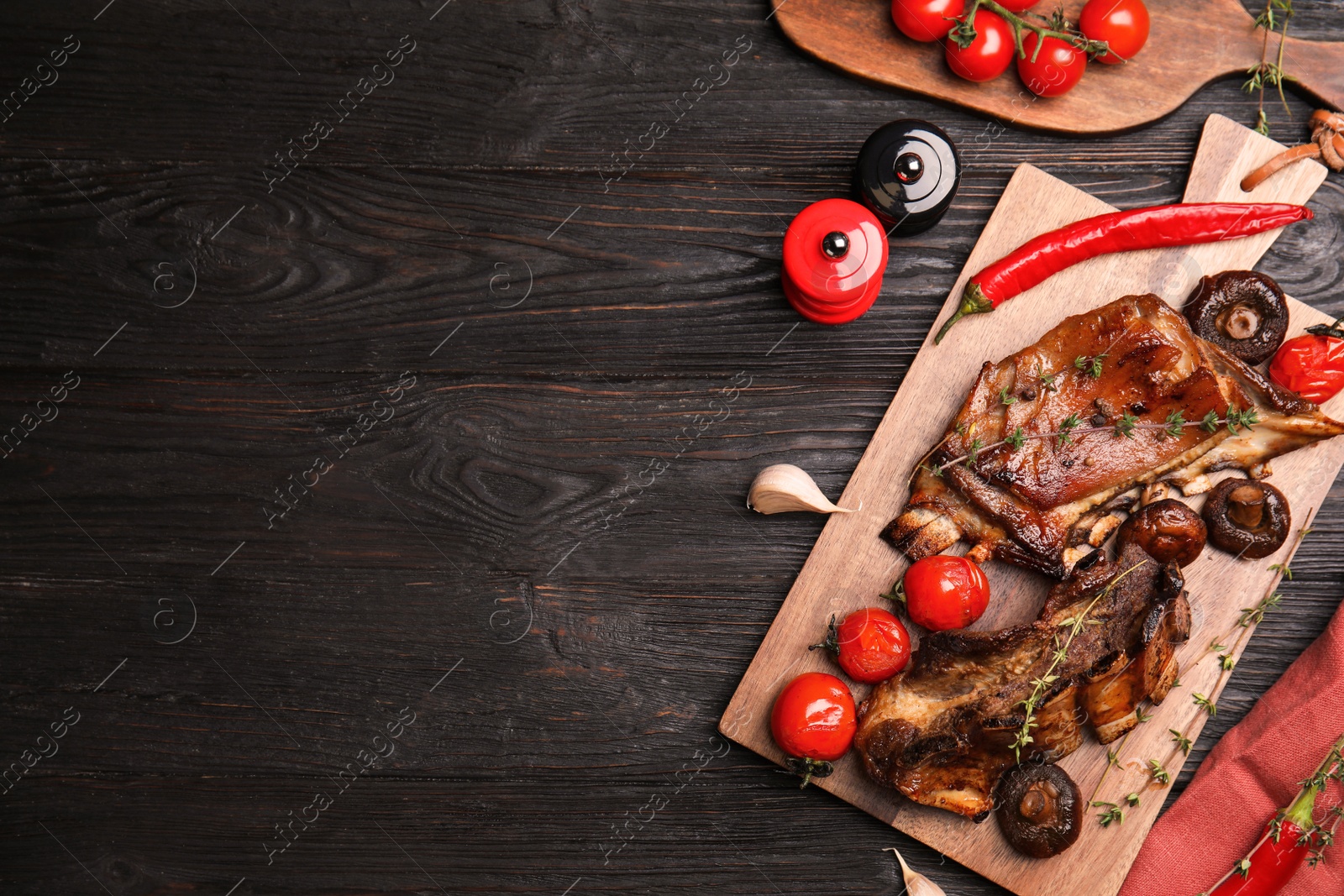 Photo of Delicious roasted ribs served on black wooden table, flat lay. Space for text