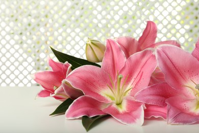 Photo of Beautiful pink lily flowers on white table, closeup