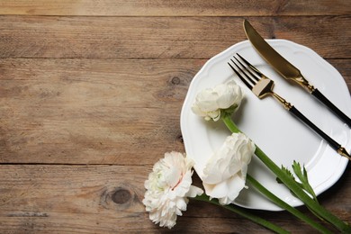 Stylish table setting with cutlery and flowers on wooden background, flat lay. Space for text