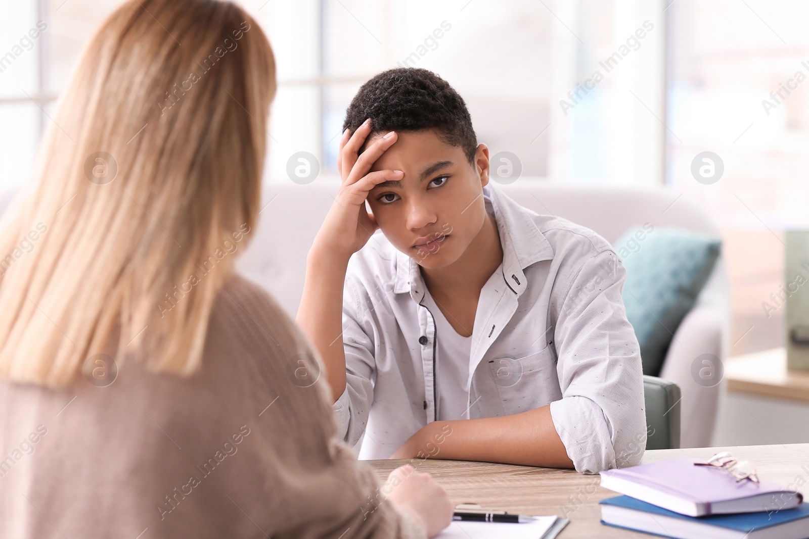 Photo of Young female psychologist working with teenage boy in office