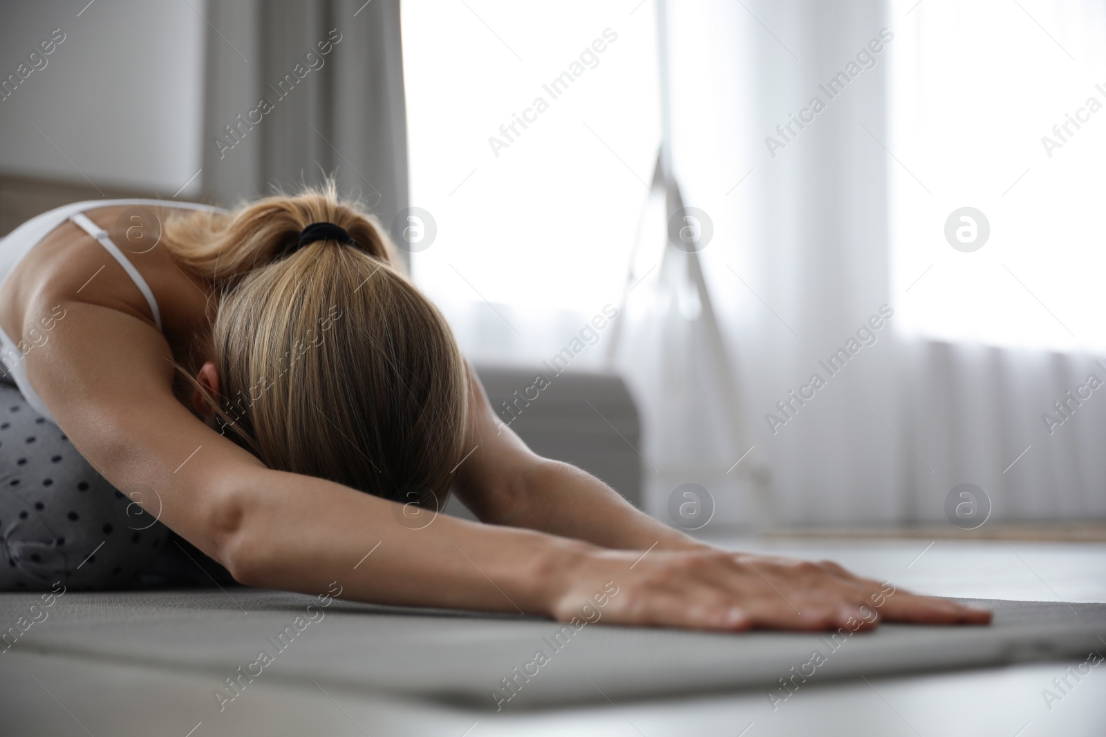 Photo of Young woman doing gymnastics on floor at home. Morning fitness