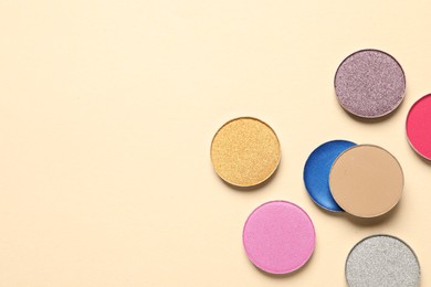 Different beautiful eye shadows on beige background, flat lay. Space for text