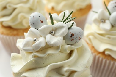 Photo of Tasty Easter cupcakes with vanilla cream on table, closeup