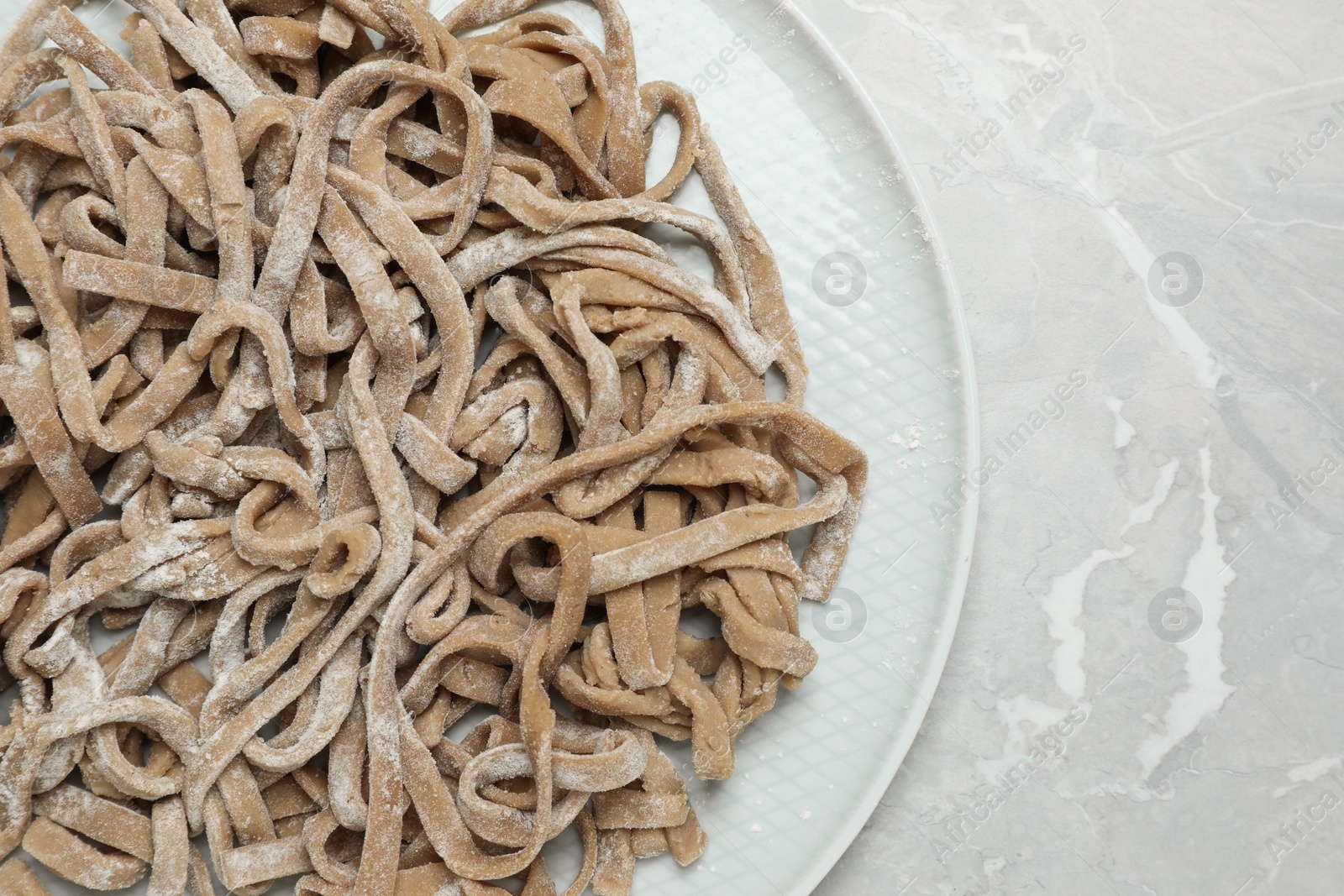 Photo of Uncooked homemade soba (buckwheat noodles) on grey table, top view