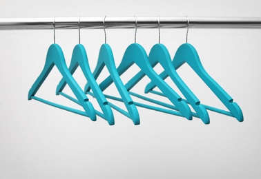 Clothes hangers on metal rail against light background