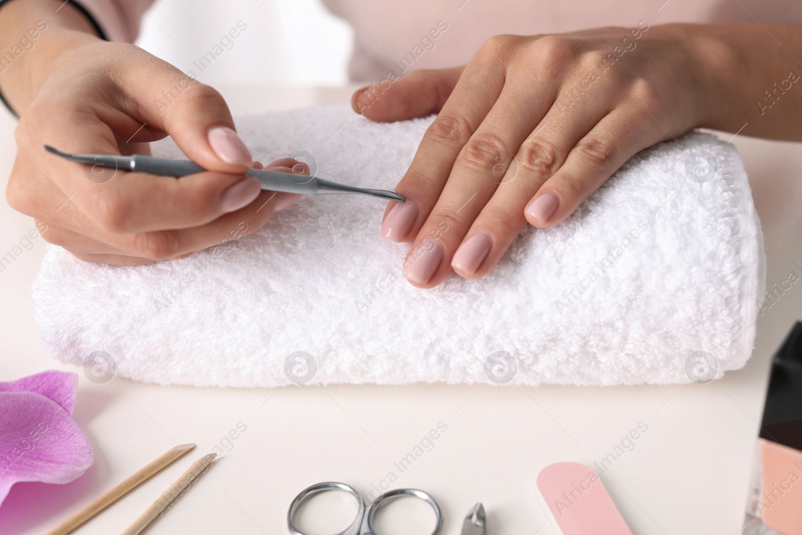 Photo of Woman preparing fingernail cuticles at table, closeup. At-home manicure