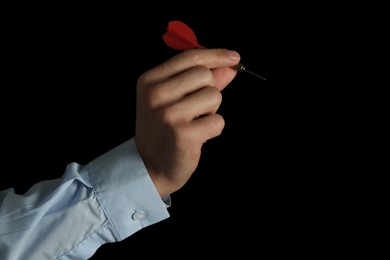 Photo of Man holding red dart on black background, closeup