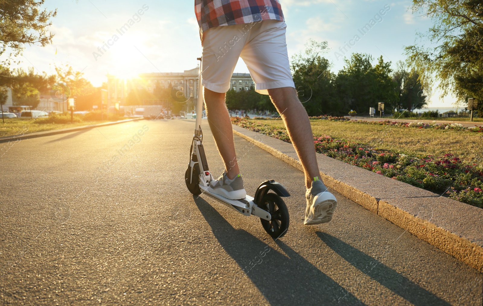 Photo of Man riding modern kick scooter in park, closeup