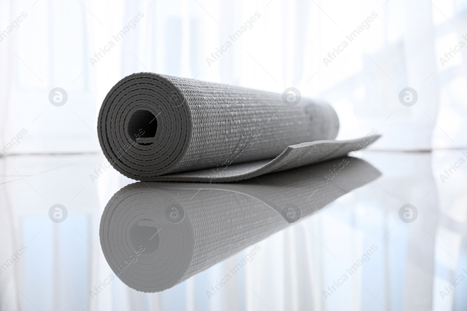 Photo of Rolled karemat or fitness mat on tiled floor