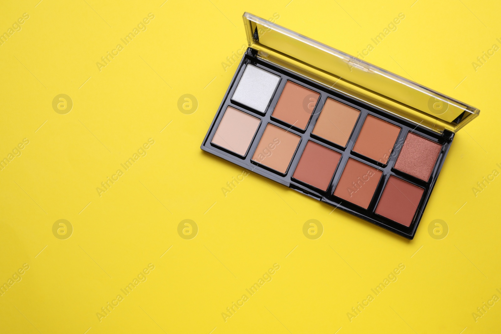 Photo of Colorful contouring palette on yellow background, top view with space for text. Professional cosmetic product